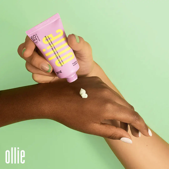 Mão com pele clara aplica creme hidratante para as mãos da Ollie em mão com pele escura.