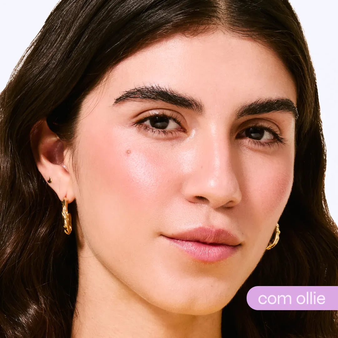 Close-up de mulher com pele radiante e blush rosado após usar bastão com cor, brincos dourados